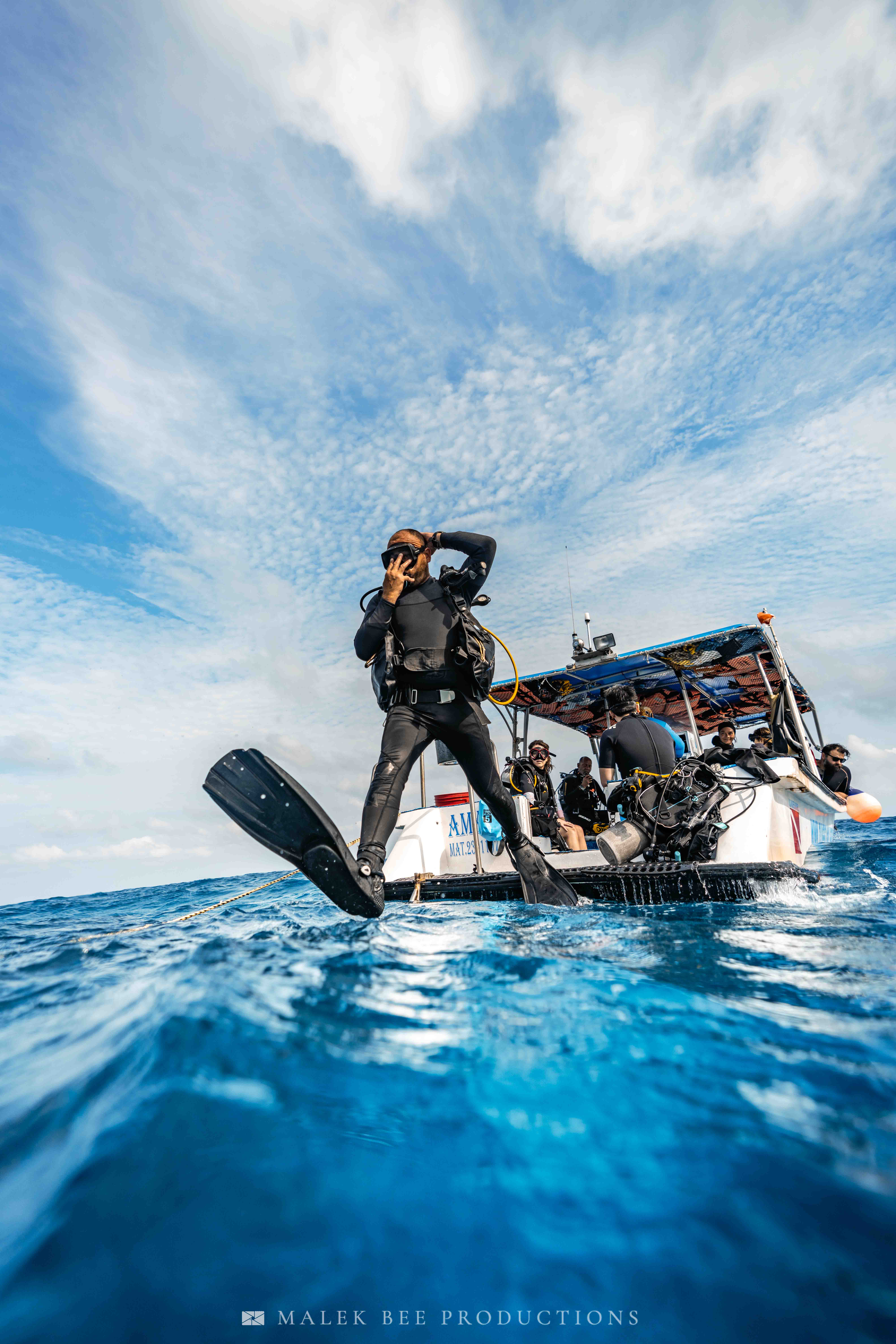 Scuba diver performing a giant stride entry from a boat into the blue ocean.